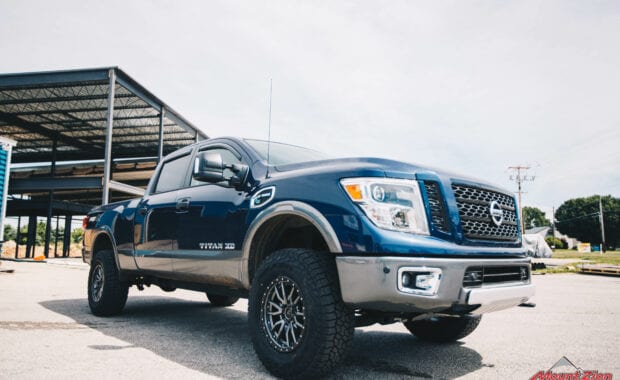 2017 Nissan Titan XD Icon suspension on Fuel Offroad REBEL 6 18x9 +20mm and LT295/70R18/10 129/126R FAL WILDPEAK A/T3W front passenger side grille view