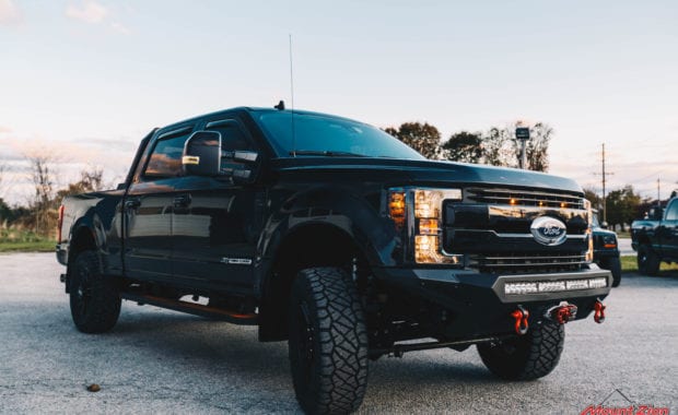Black 2019 F250 with black wheels and offroad bumper with winch and lighting front passenger side grille view