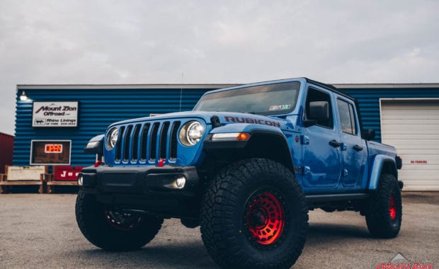 Blue Jeep Gladiator soft top with Red fuel wheels front driver side grille view