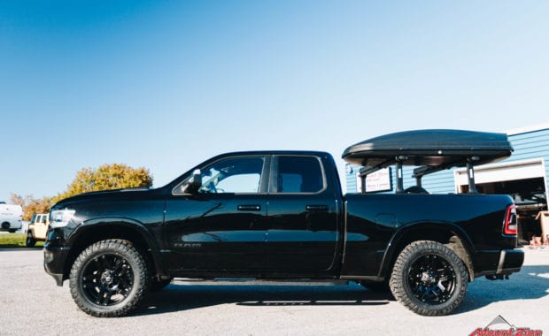 Black Dodge Ram with black wheels Thule bed rack driver side view