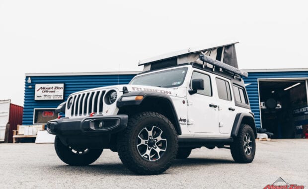 White Jeep Wrangler with Ursa Minor J30 Camper Top and ARB Awning front driver side grille view