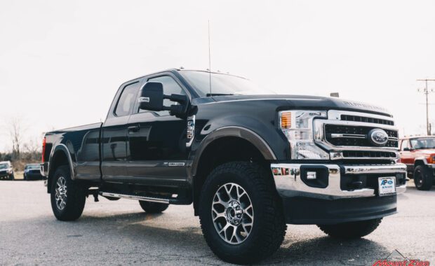 2020 Black F-350 with readylift 2.5 leveling kit and geolander tires front passenger side grille view